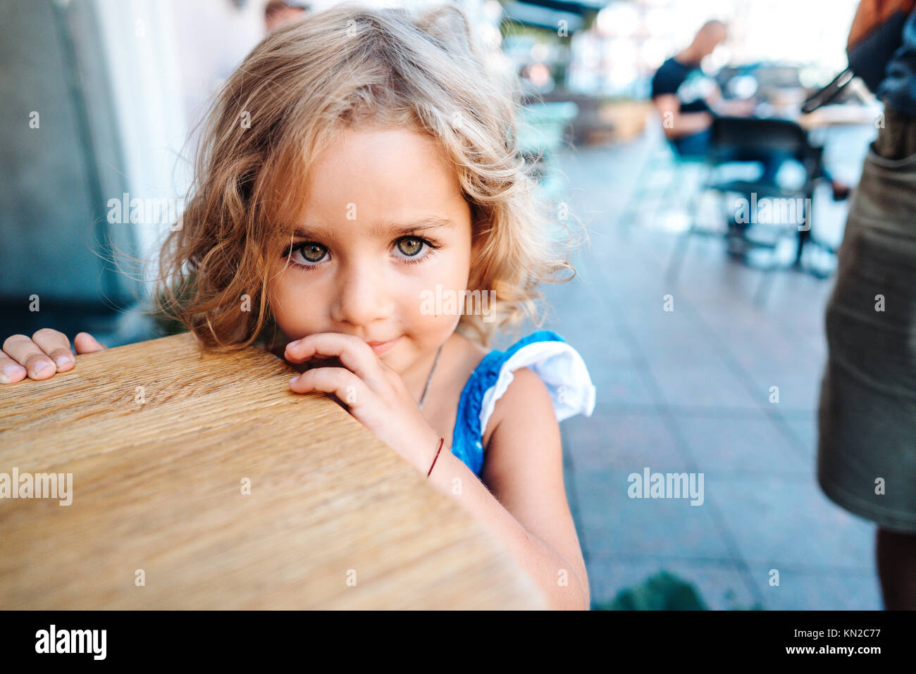 Little girl in a blue dress near a small table Stock Photo