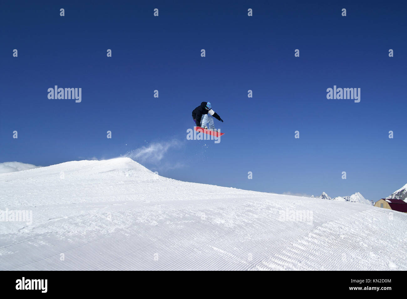 Snowboarder jump in terrain park at ski resort on sunny winter day. Caucasus Mountains, region Dombay. Stock Photo