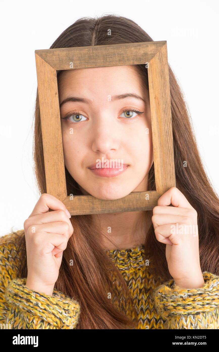 Beautiful teenage girl looking through a small wooden frame Stock Photo
