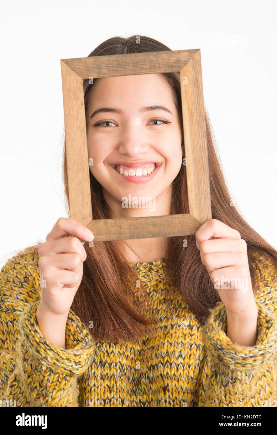 Beautiful teenage girl looking through a small wooden frame Stock Photo