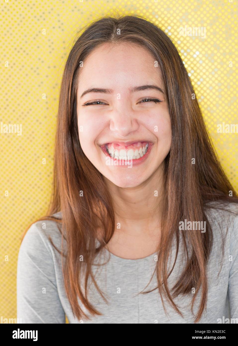 Playful teenage girl having fun and laughing in front of funky yellow dotted background Stock Photo