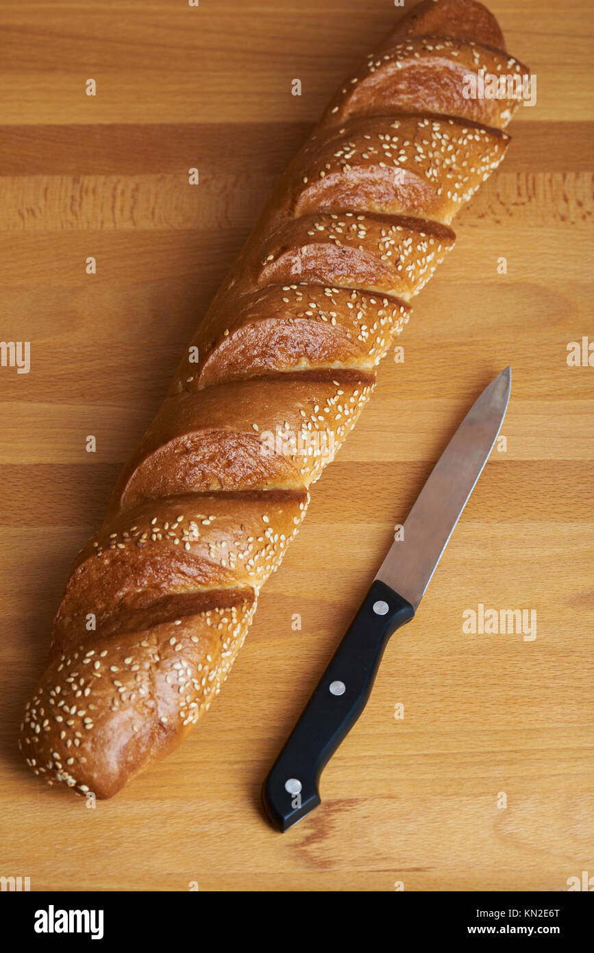 Fresh baguette on wooden table lay with black knife top view Stock Photo