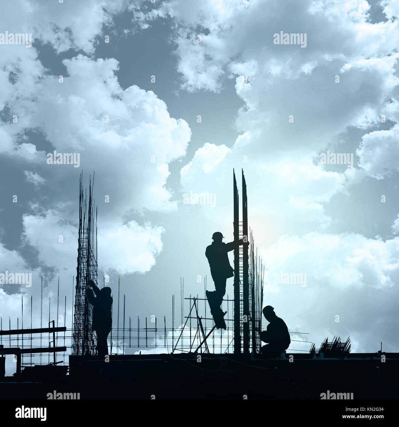 Unrecognizable silhouettes of builders against the background of a colorful sunset Stock Photo