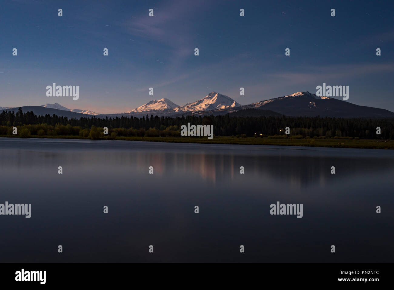 View of the Cascade Mountains from Black Butte Ranch at Night with Star Trails and Reflections in the Lake Stock Photo