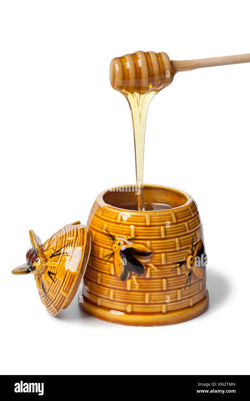 Classic ceramic honey pot with dipper and honeyon white background