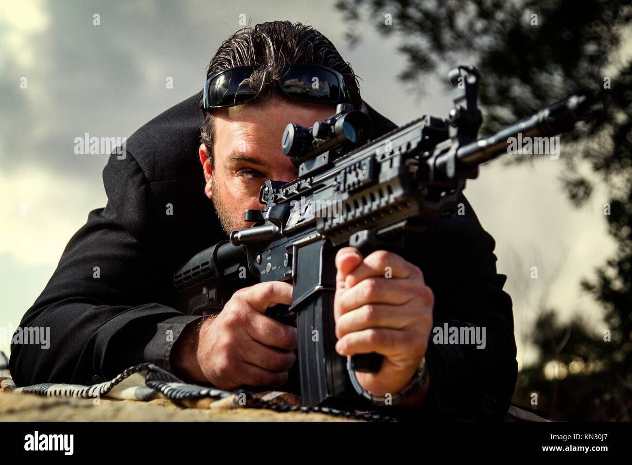 View of a contracted type killer agent wandering with a long jacket and machine gun. Stock Photo