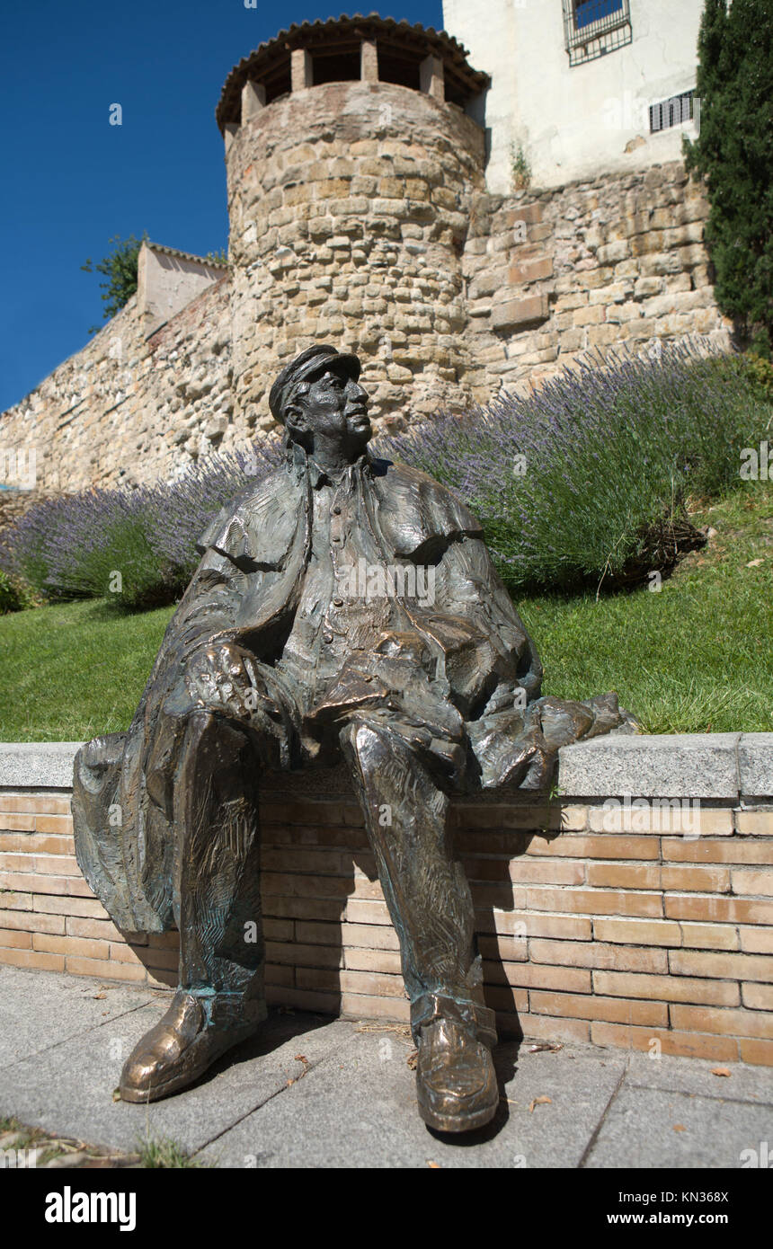 Statue of Jose Ledesma, Salamanca poet. The sculpture depicts him wearing his trademark layer Salamanca, sitting next to the wall of Salamanca, as Stock Photo