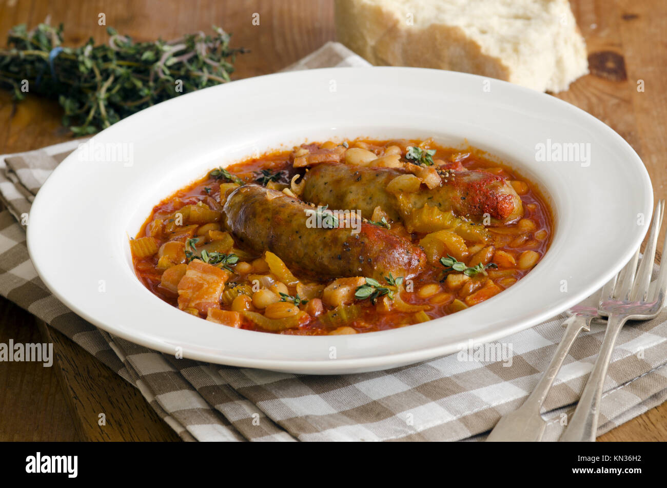 Grilled sausages with white beans, herbs and bacon lardons Stock Photo