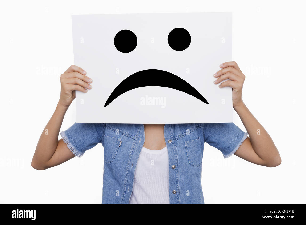 Blonde Young girl holding a sign with a sad smiles face front of her. Stock Photo