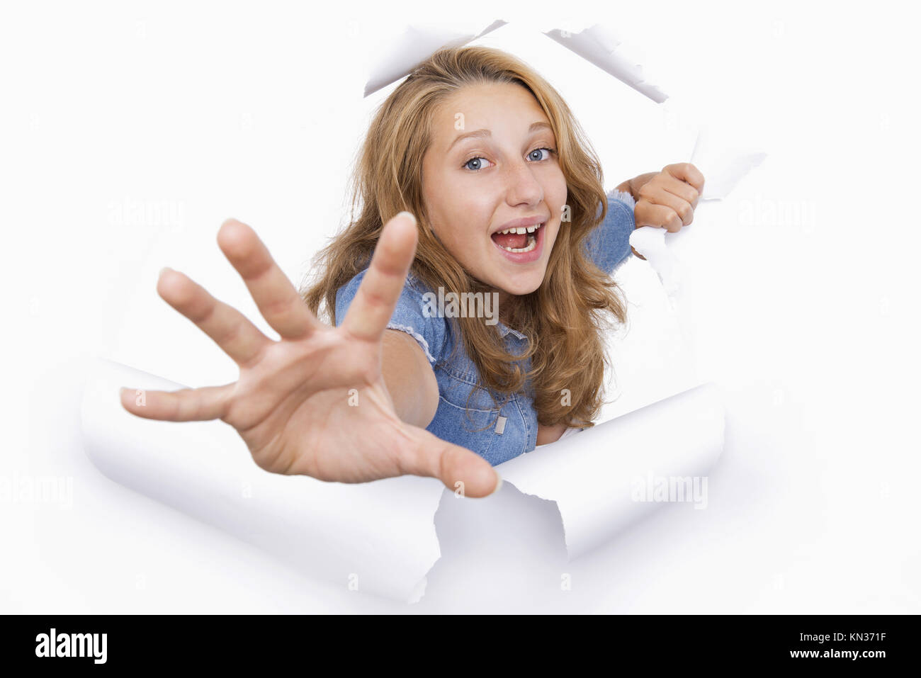 Young woman coming out of a hole tearing on the white paper. Stock Photo