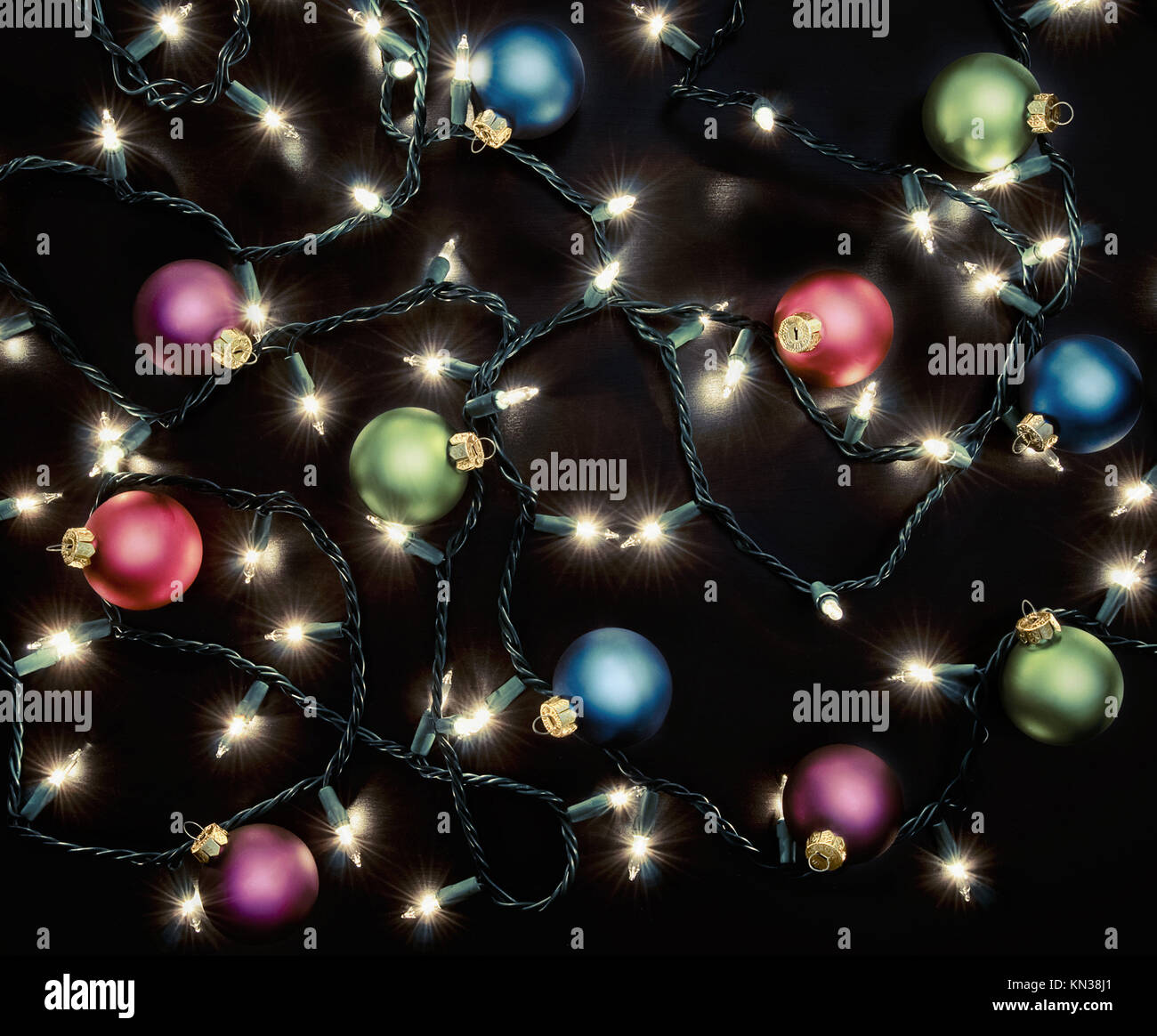 A Strand of Christmas lights and round ornaments over a dark background