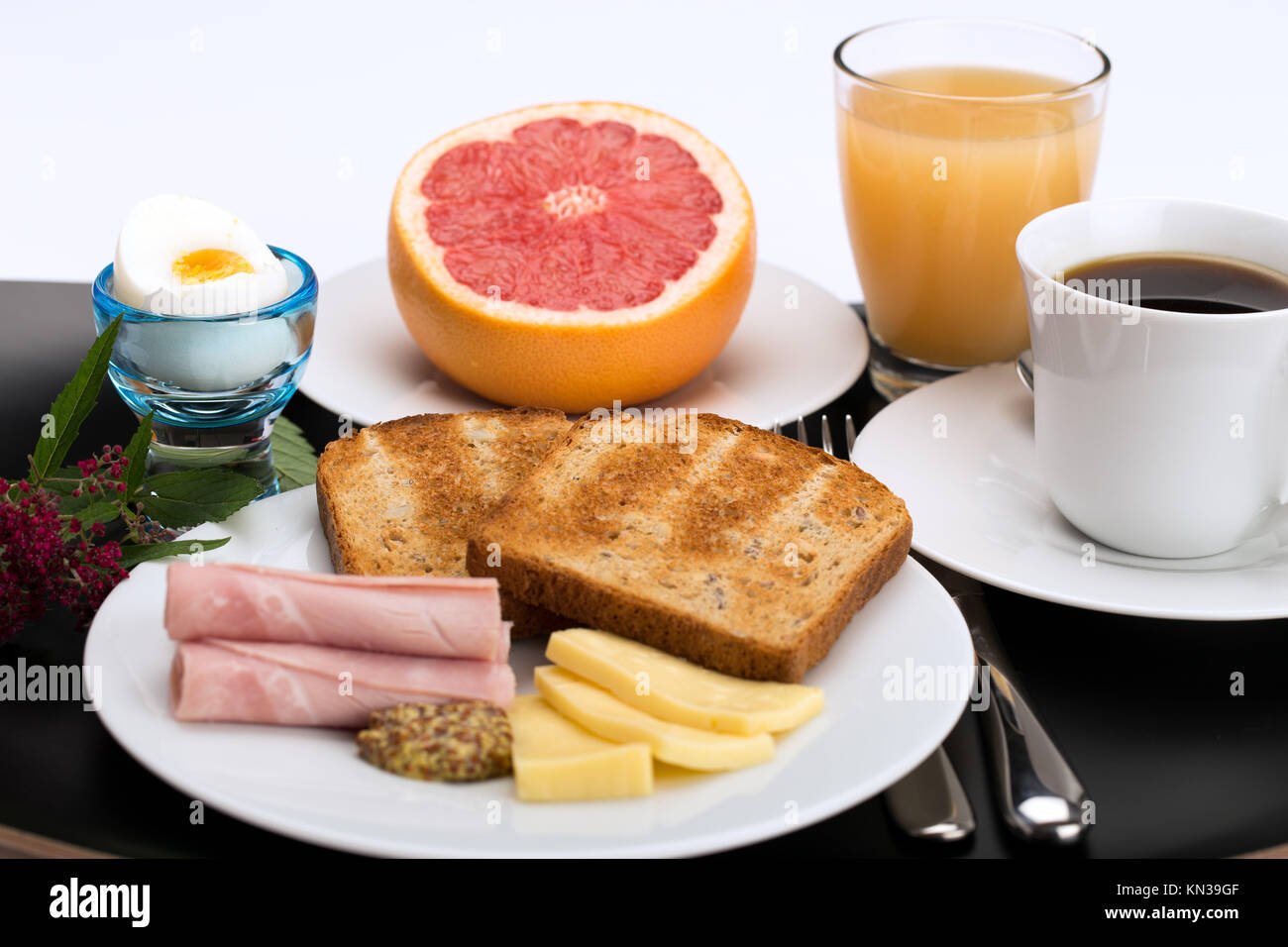 Breakfast with toast, ham, cheese, egg, grapefruit, juice and cup of