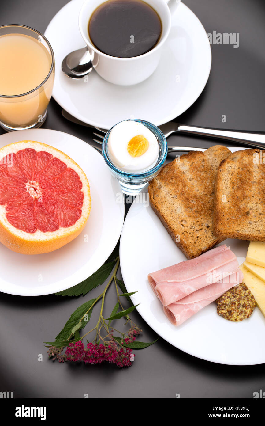 Breakfast with toast, ham, cheese, egg, grapefruit, juice and cup of