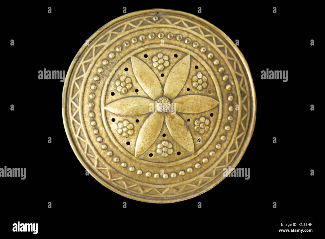 Antique heater made of brass decorated with floral figures. Isolated over black background. Stock Photo