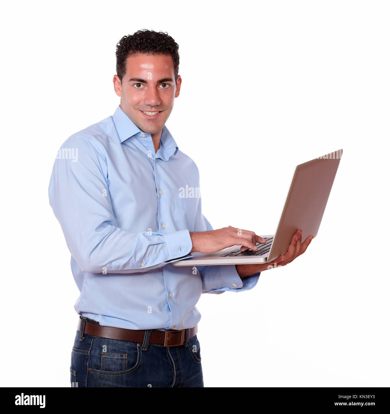 Portrait of a charismatic male using his laptop computer while smiling at you on isolated studio. Stock Photo