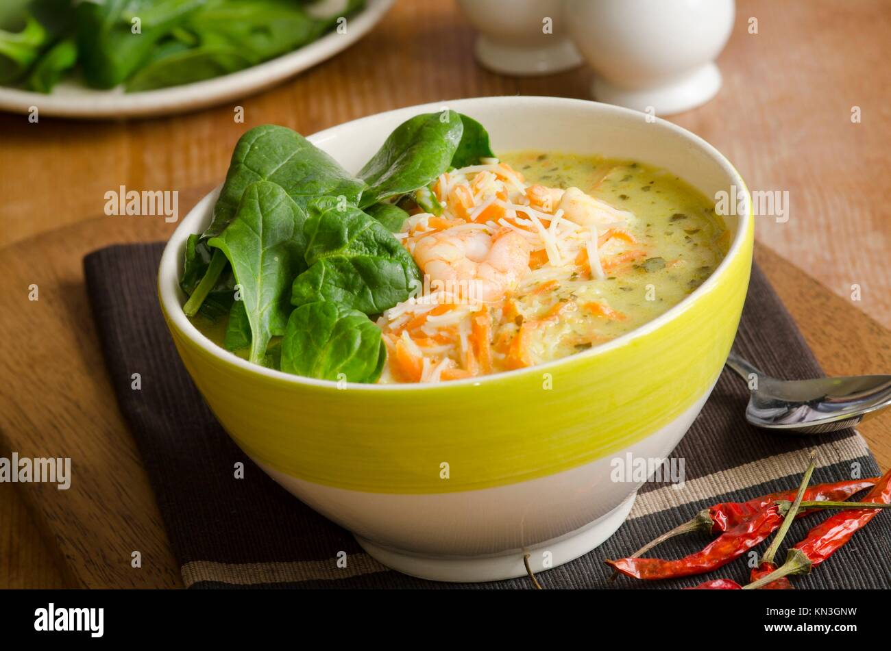 A spicy fragrant prawn laksa soup topped with spinach. Stock Photo