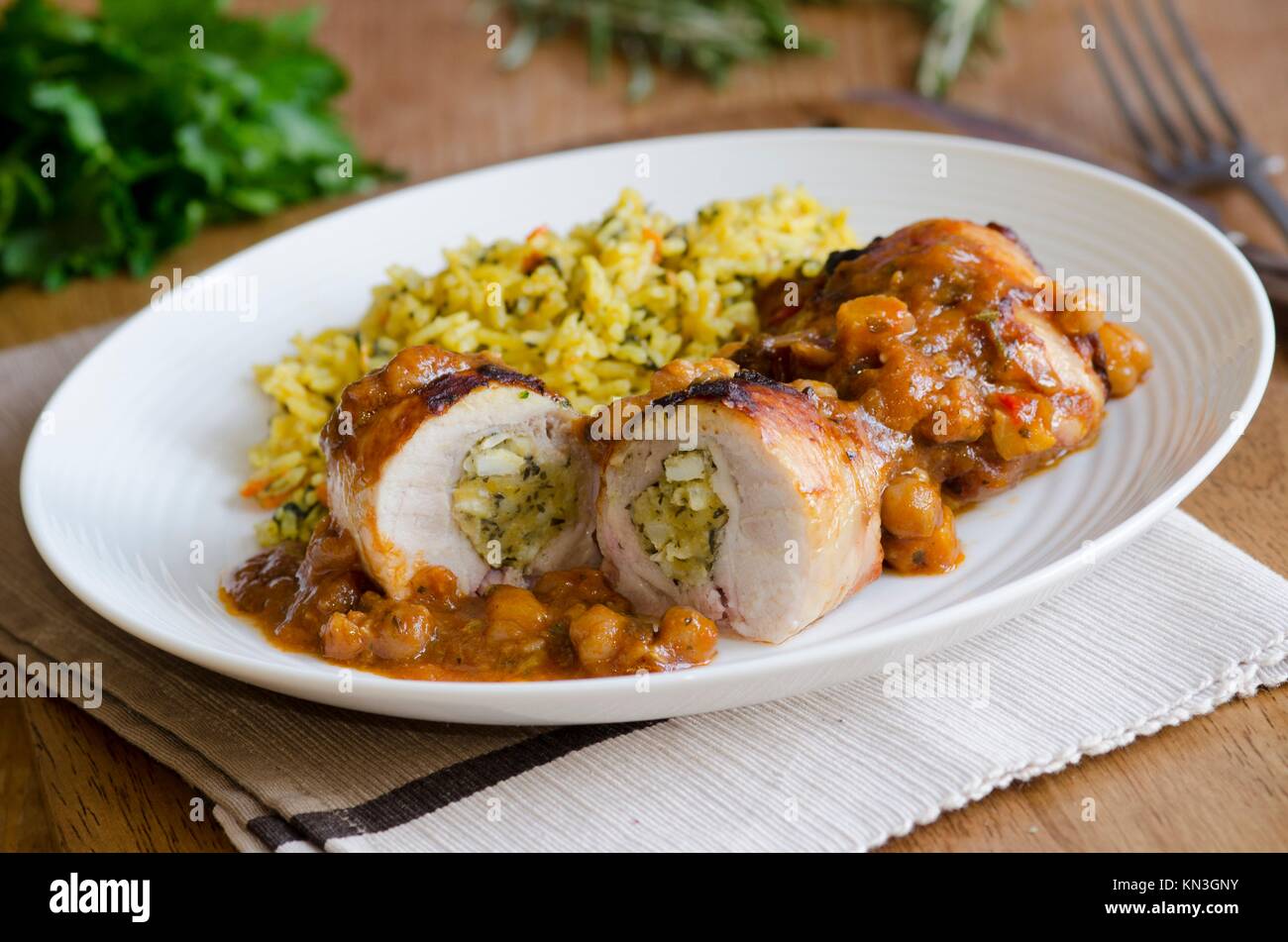 Stuffed chicken thighs in an aromatic spiced tagine sauce with carrot pilau rice. Stock Photo