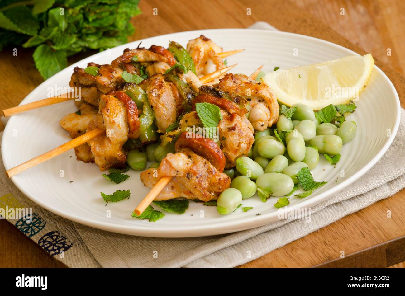 Grilled chicken and chorizo skewers with broad beans and mint. Stock Photo