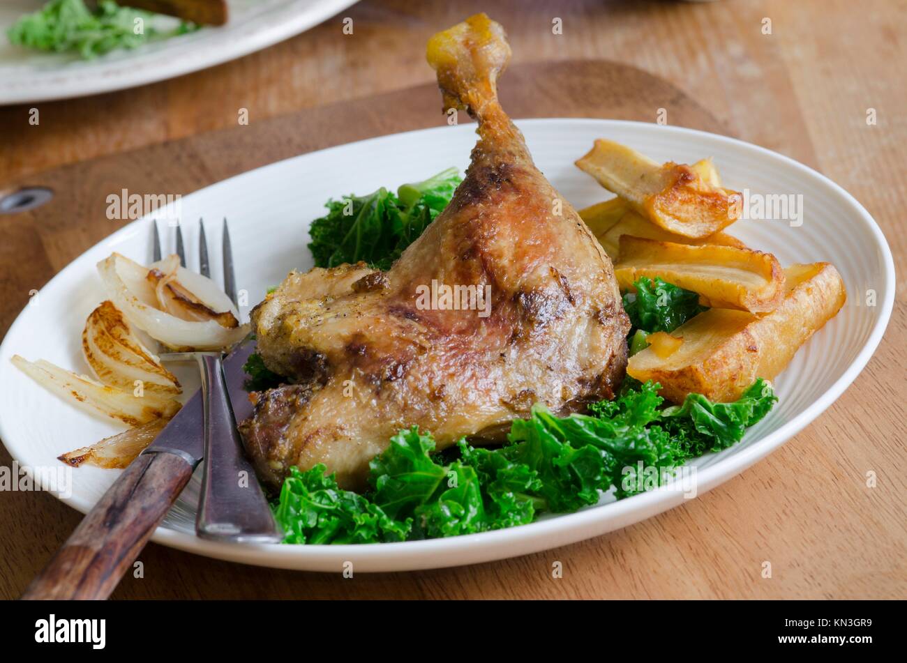 Roast duck legs with steamed kale and roast parsnips. Stock Photo