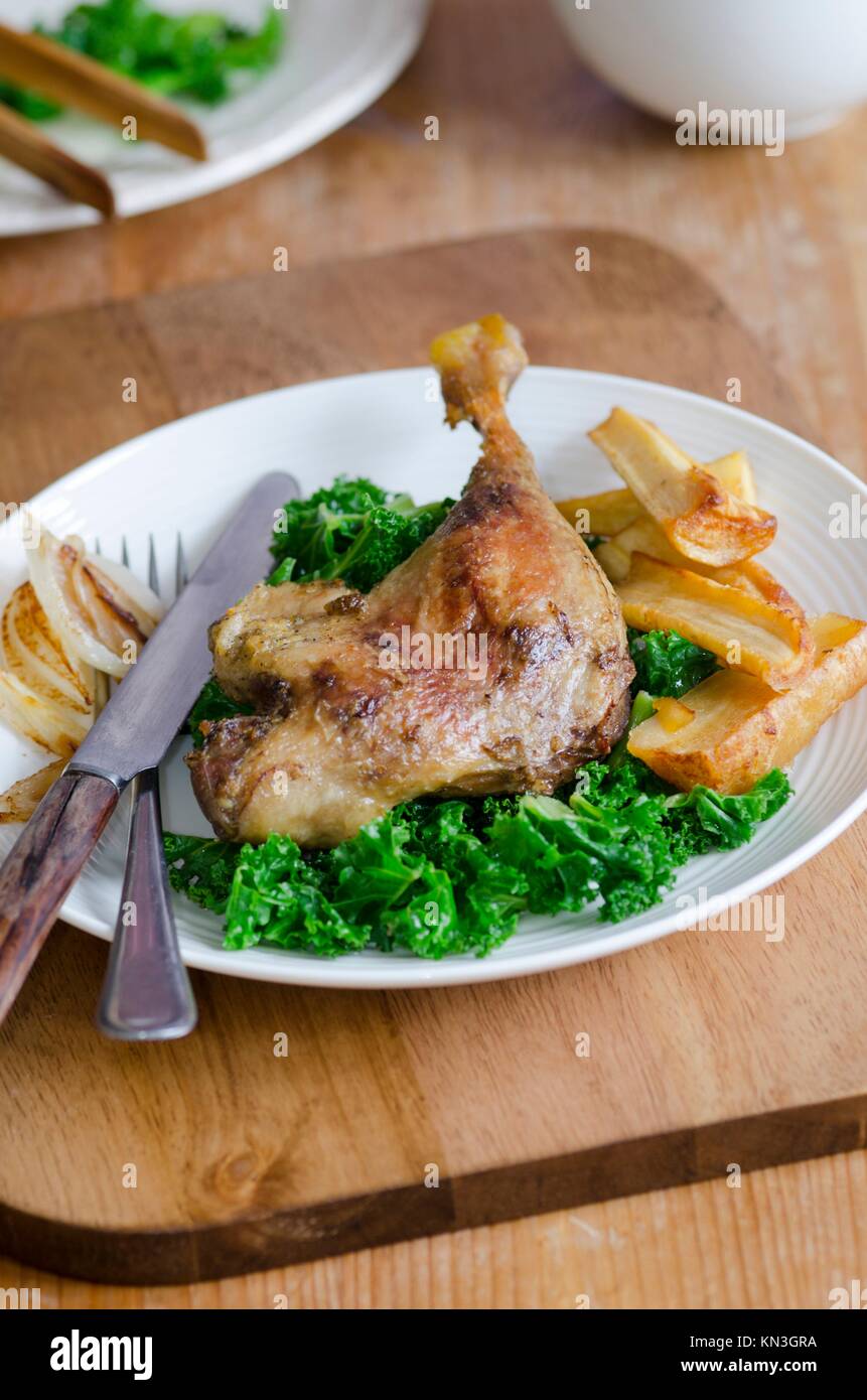 Roast duck legs with steamed kale and roast parsnips. Stock Photo
