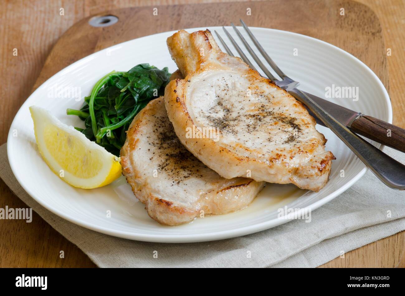 Pork chops with wilted spinach on a plate. Stock Photo