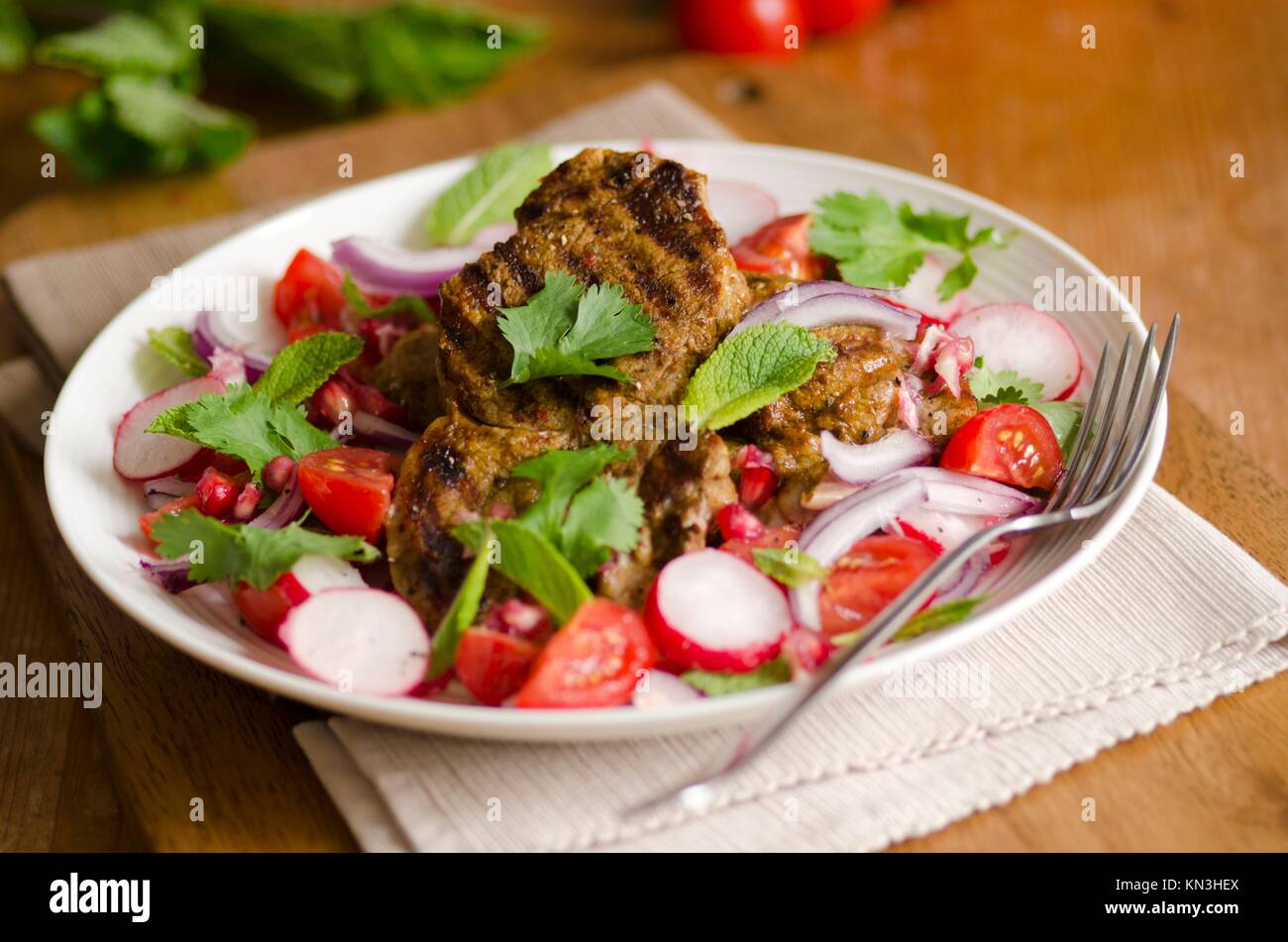 Sizzled masala lamb with chopped salad on a plate. Stock Photo