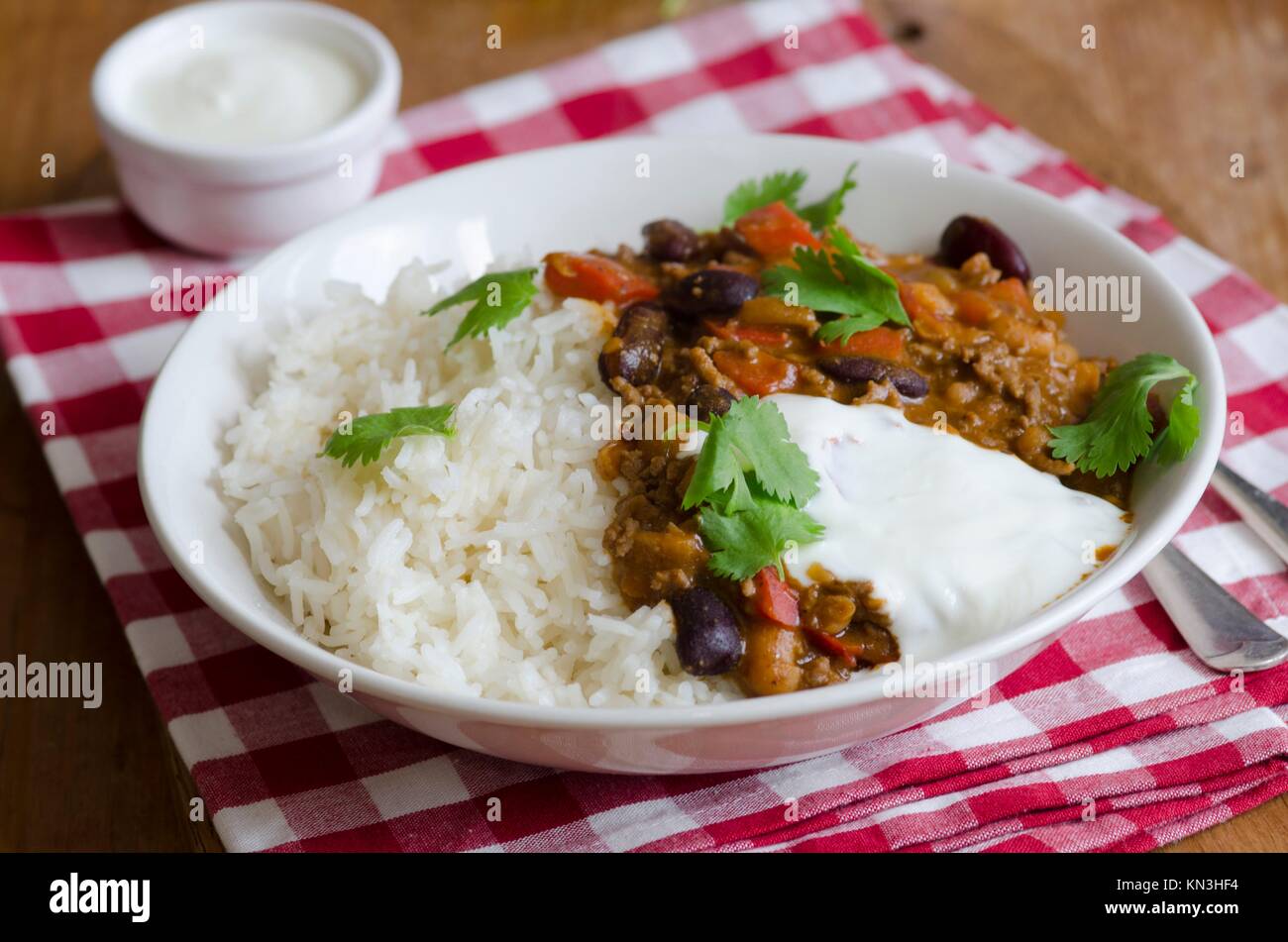 Mexican chilli with rice and cream in a bowl. Stock Photo