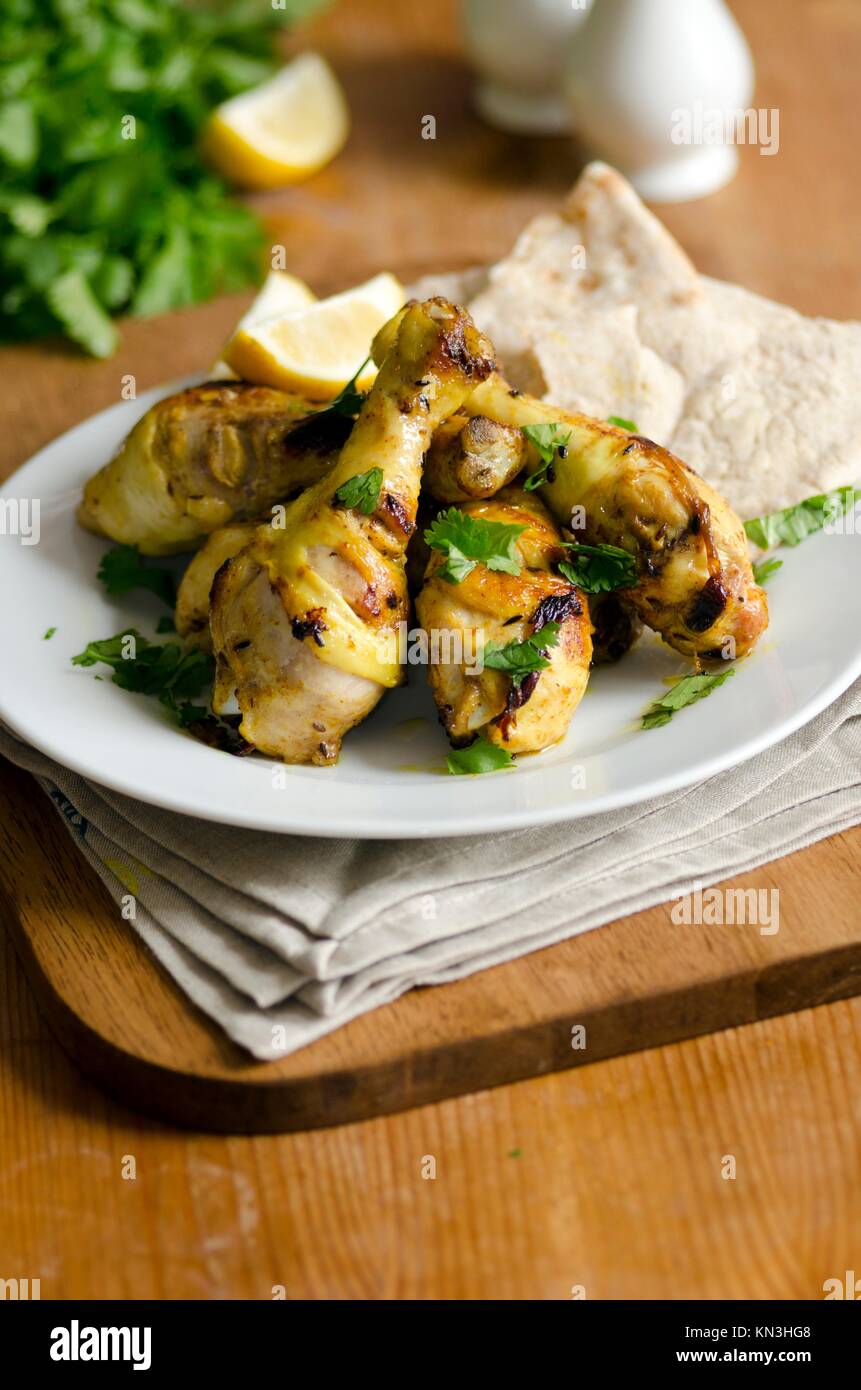 Barbequed chicken drumsticks with pitta bread. Stock Photo