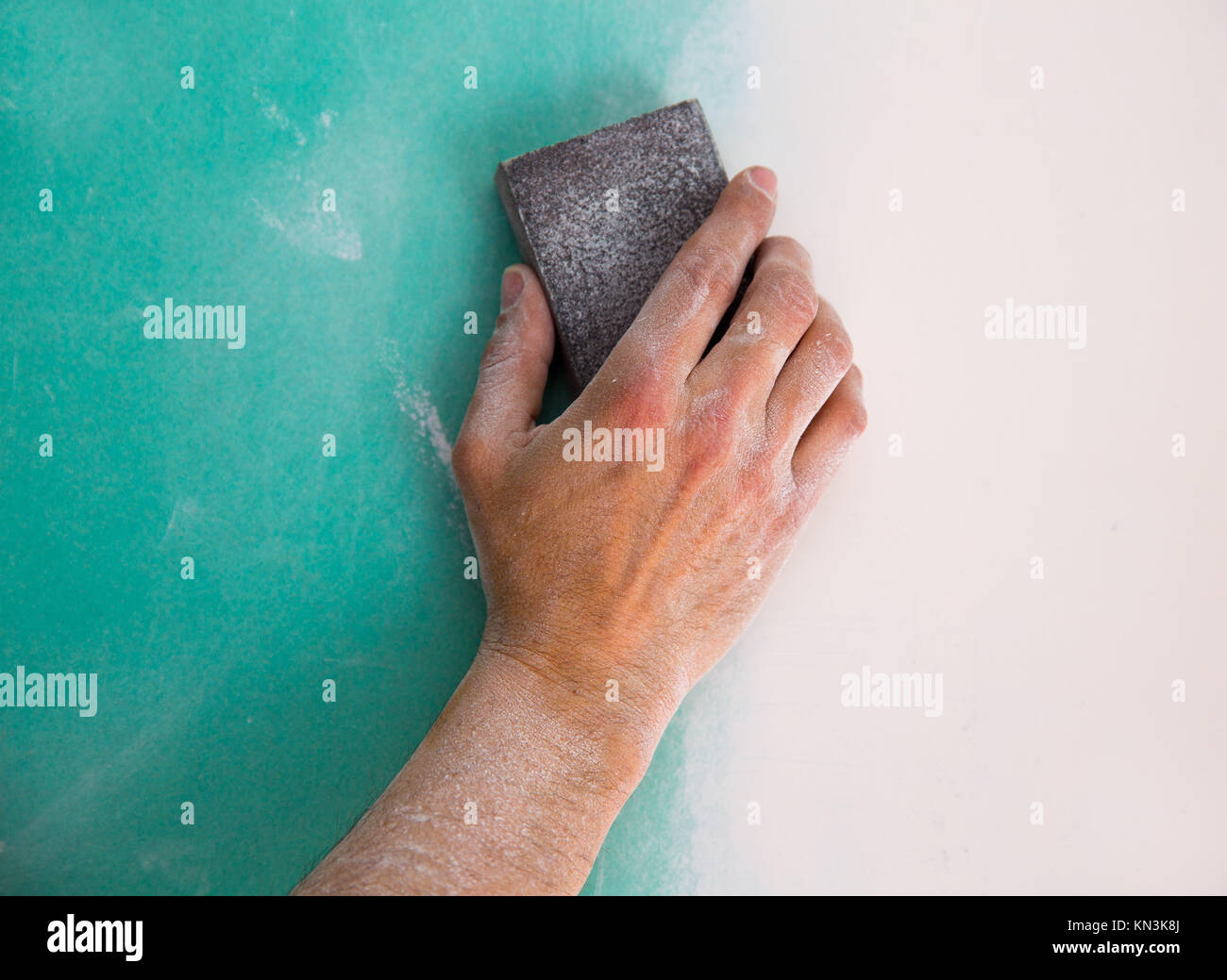plastering man hand sanding the plaste in drywall seam plasterboard. Stock Photo