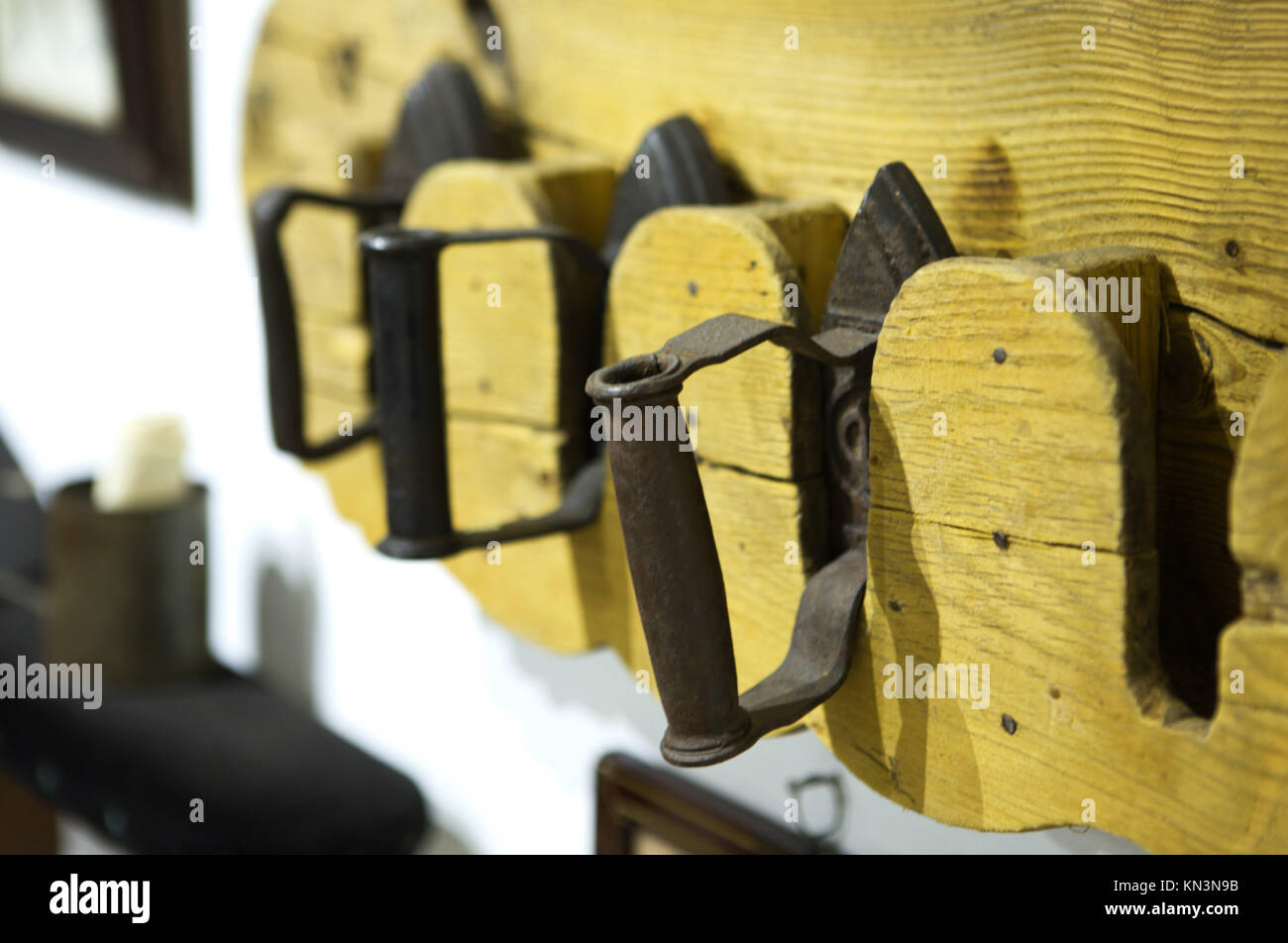 Old irons from solid metal, very heavy and rusty, set over hanging wooden stand, Badajoz, Spain. Stock Photo