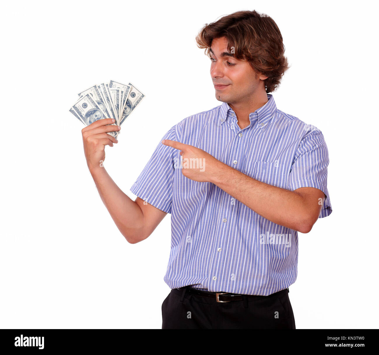 Portrait of an ambitious young man holding and pointing cash dollars while is looking on it on isolated background. Stock Photo