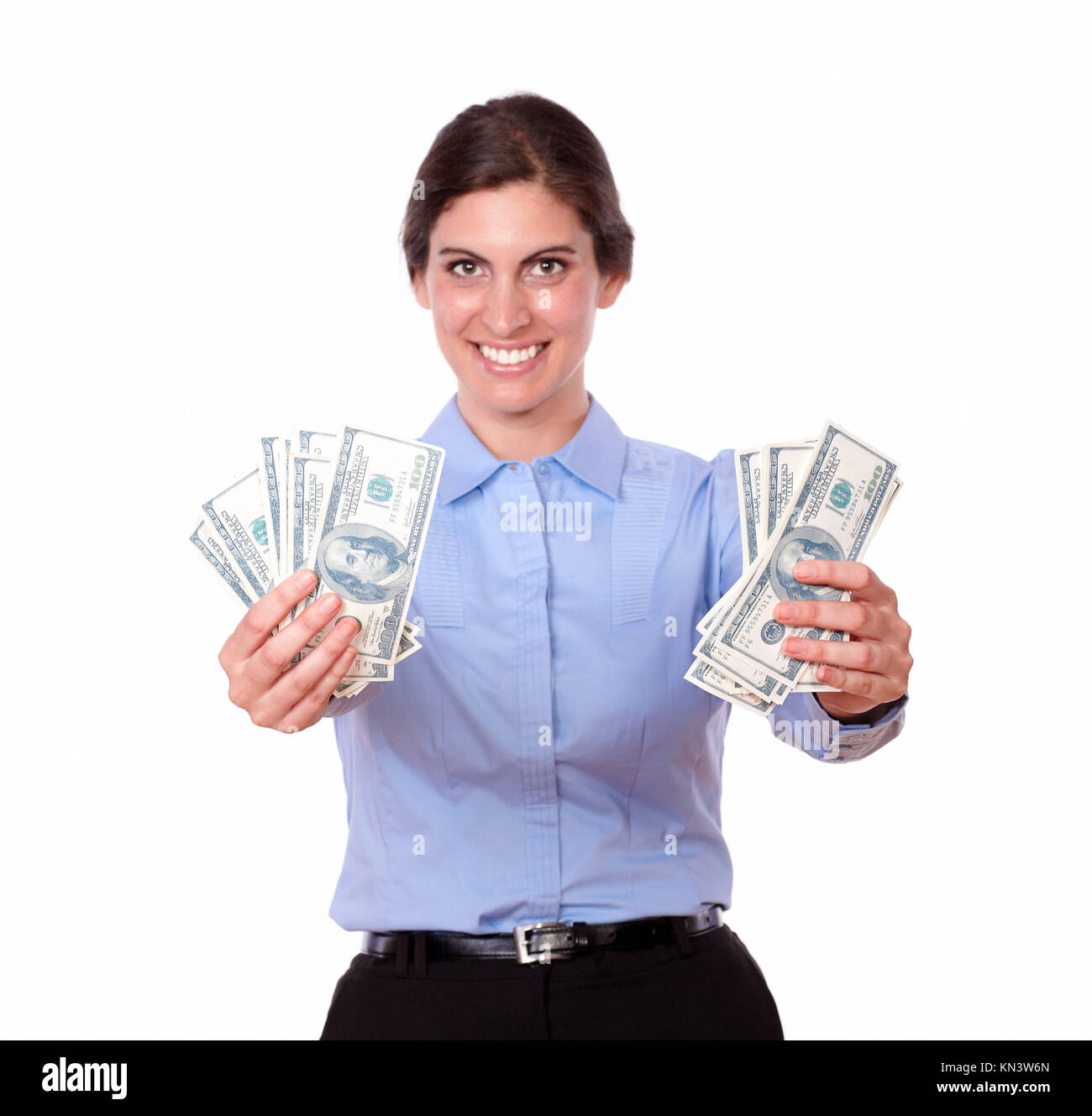 Portrait of an ambitious young woman in blue blouse smiling while holding cash dollars, on isolated white background. Stock Photo