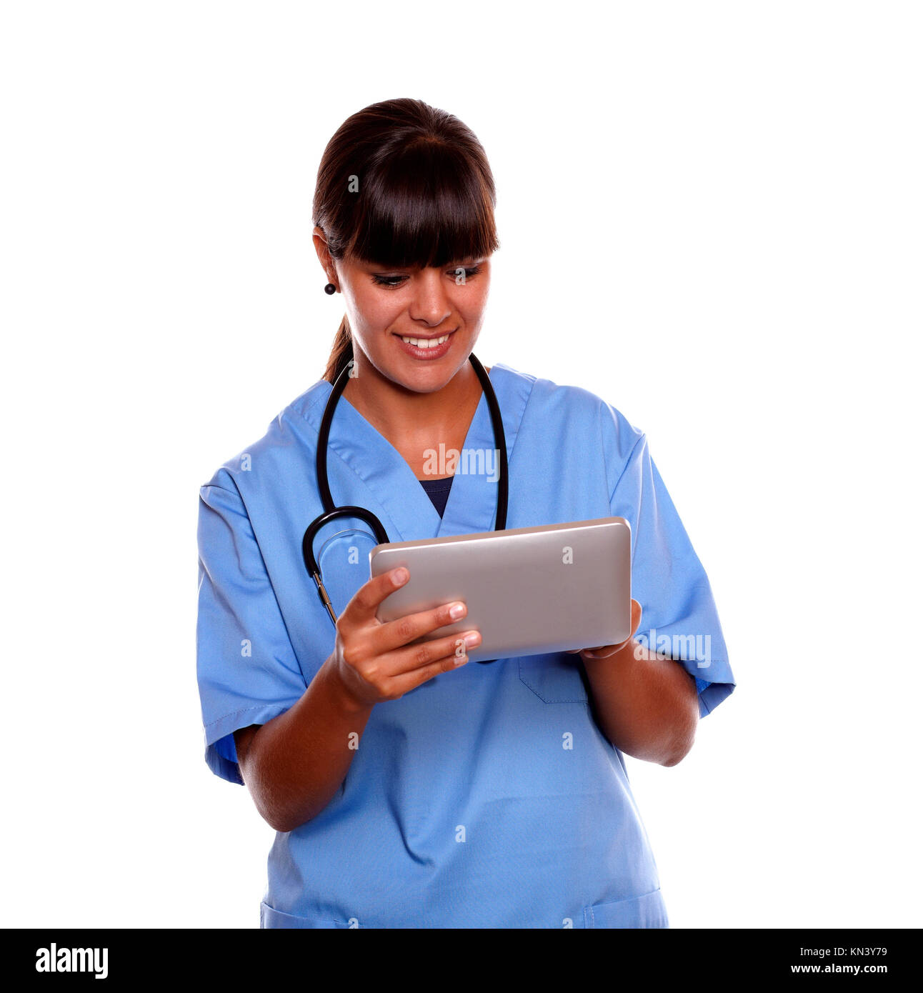 Portrait of a smiling young professional nurse using her tablet on blue uniform with a stethoscope on isolated background. Stock Photo