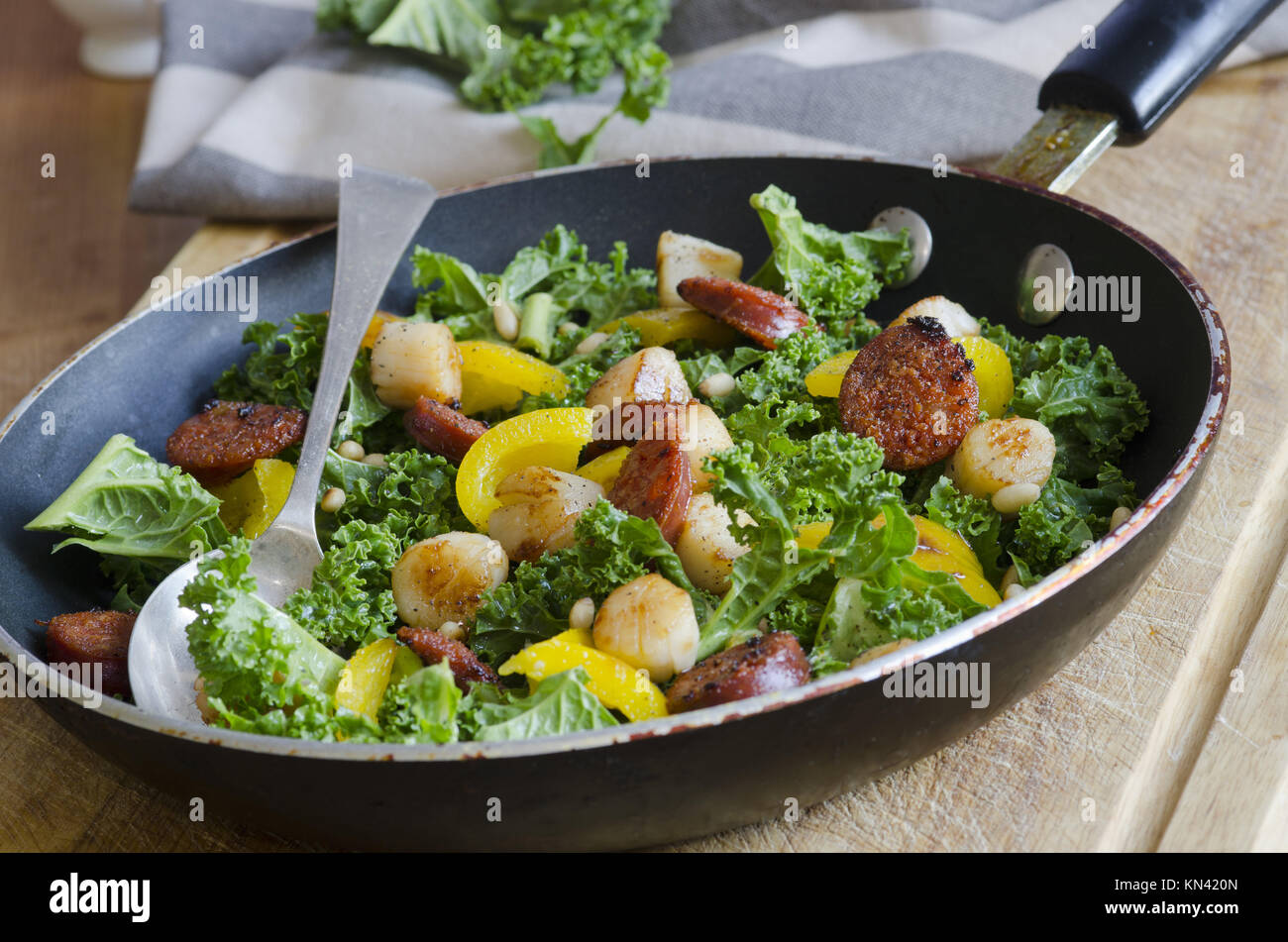 Spanish sausage, scallops, kale and yellow bell peppers in a pan Stock