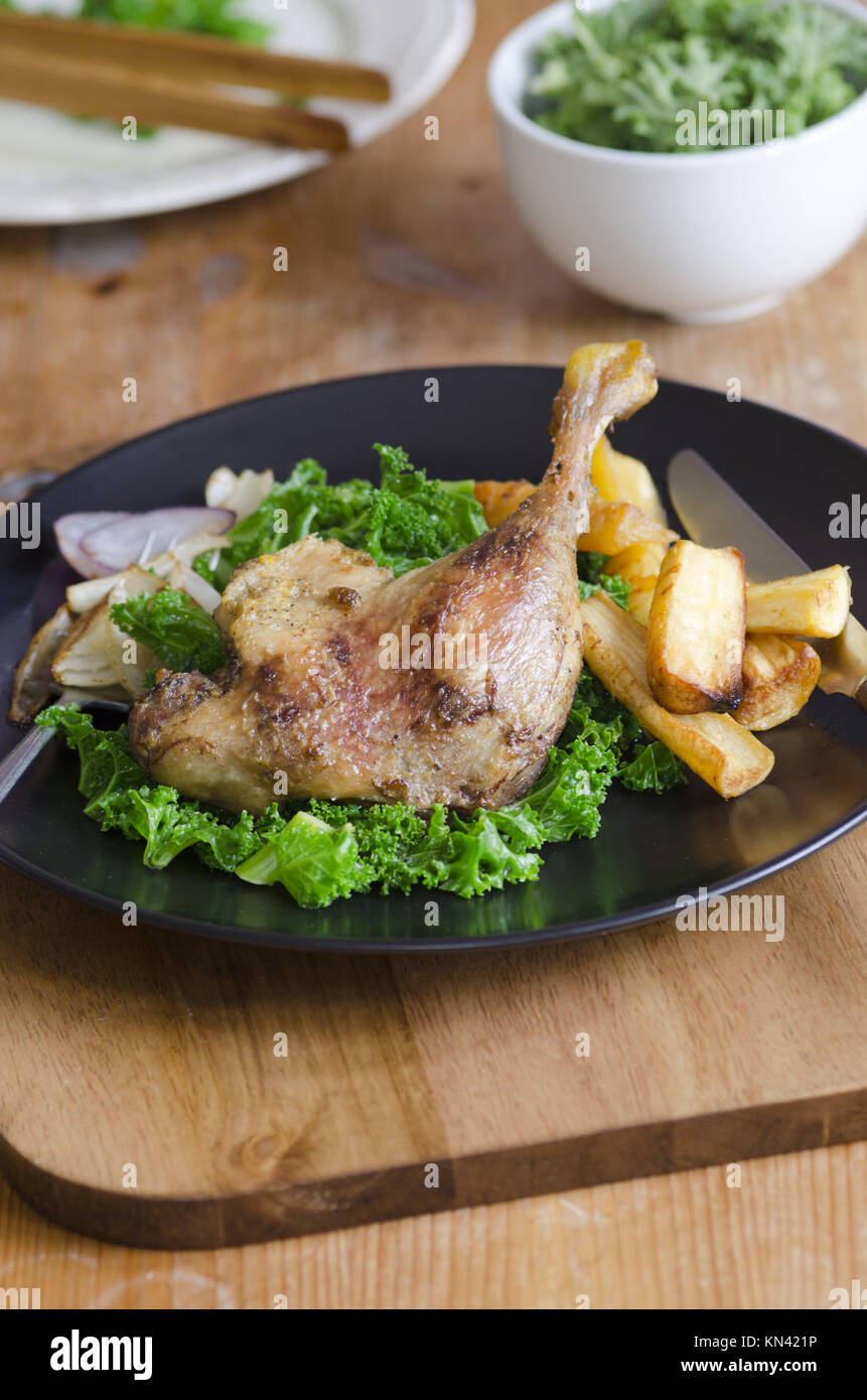Roast duck leg with steamed curly kale and roast parsnips Stock Photo