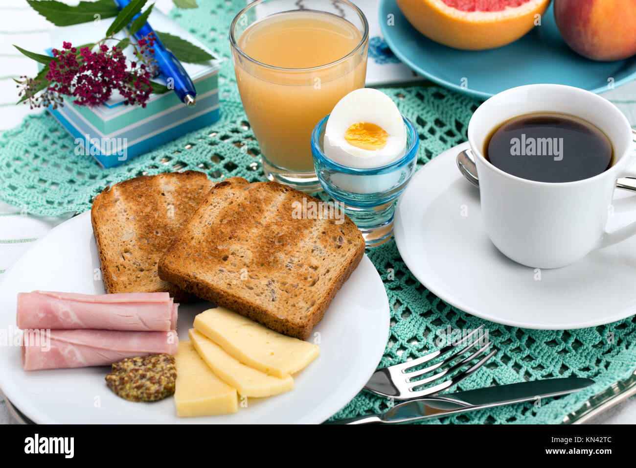 Breakfast with toast, ham, cheese, egg, grapefruit, juice and cup of