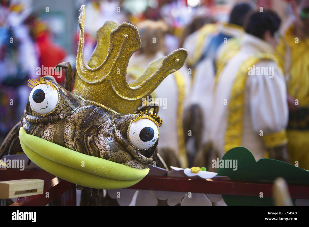Costume of crown frog resting on stand while performers make