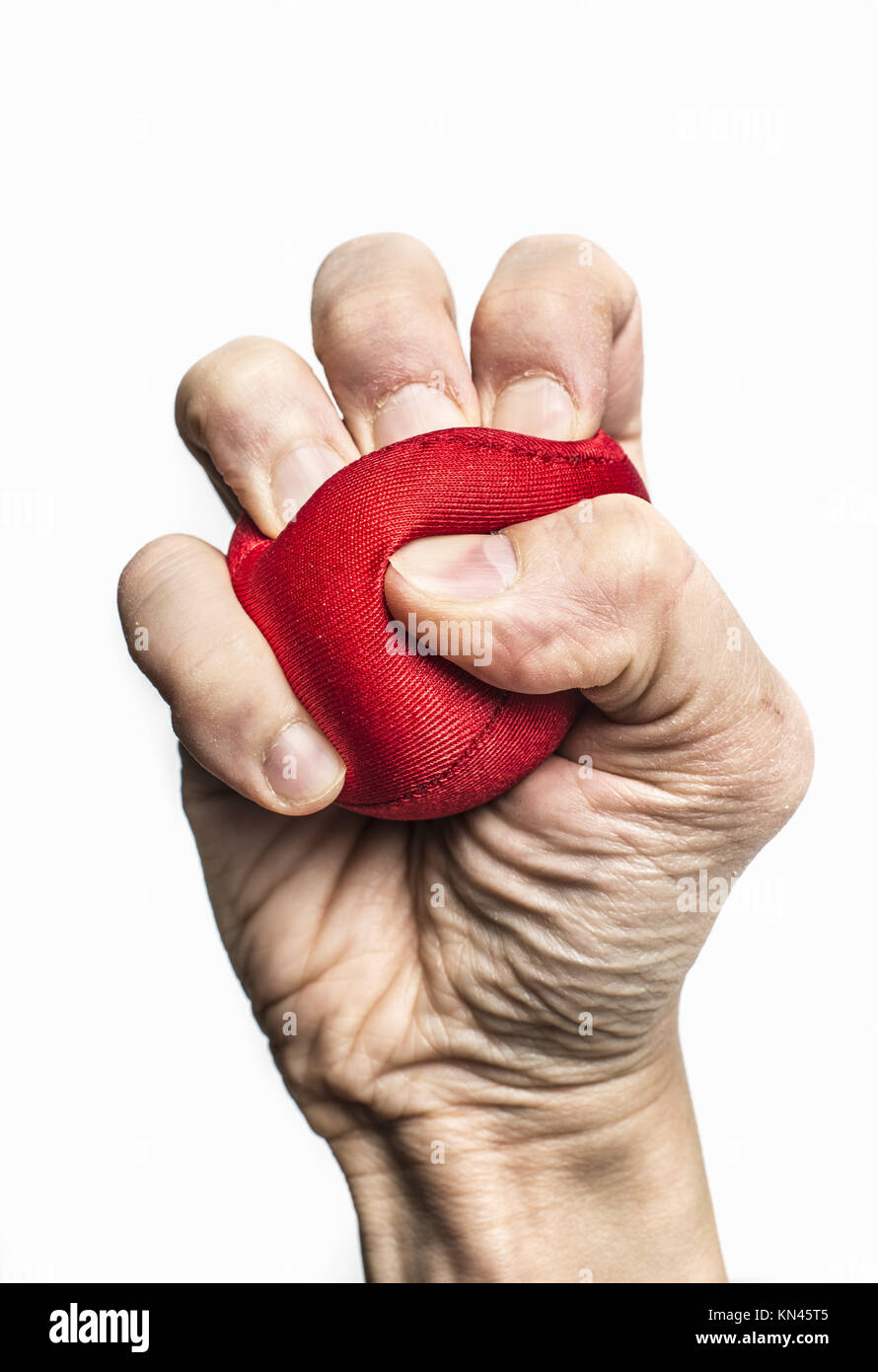 Human fist squeezing red stress ball. Symbol of anxiety, frustration and pressure at work. Stock Photo