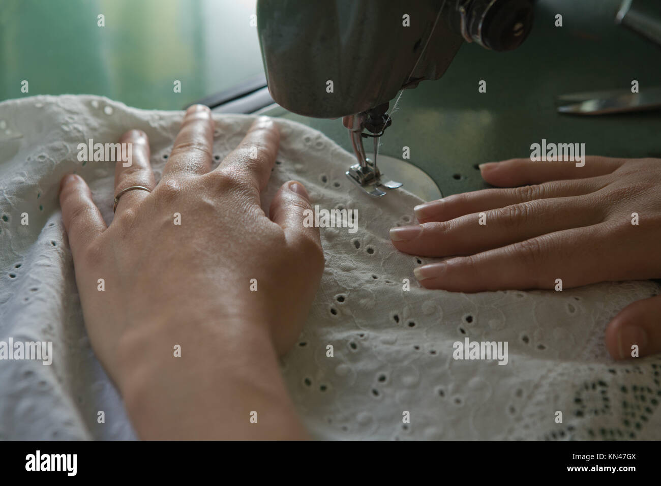 Hands of a dressmaker supporting a cloth while sewing on a sewing machine, Spain. Stock Photo