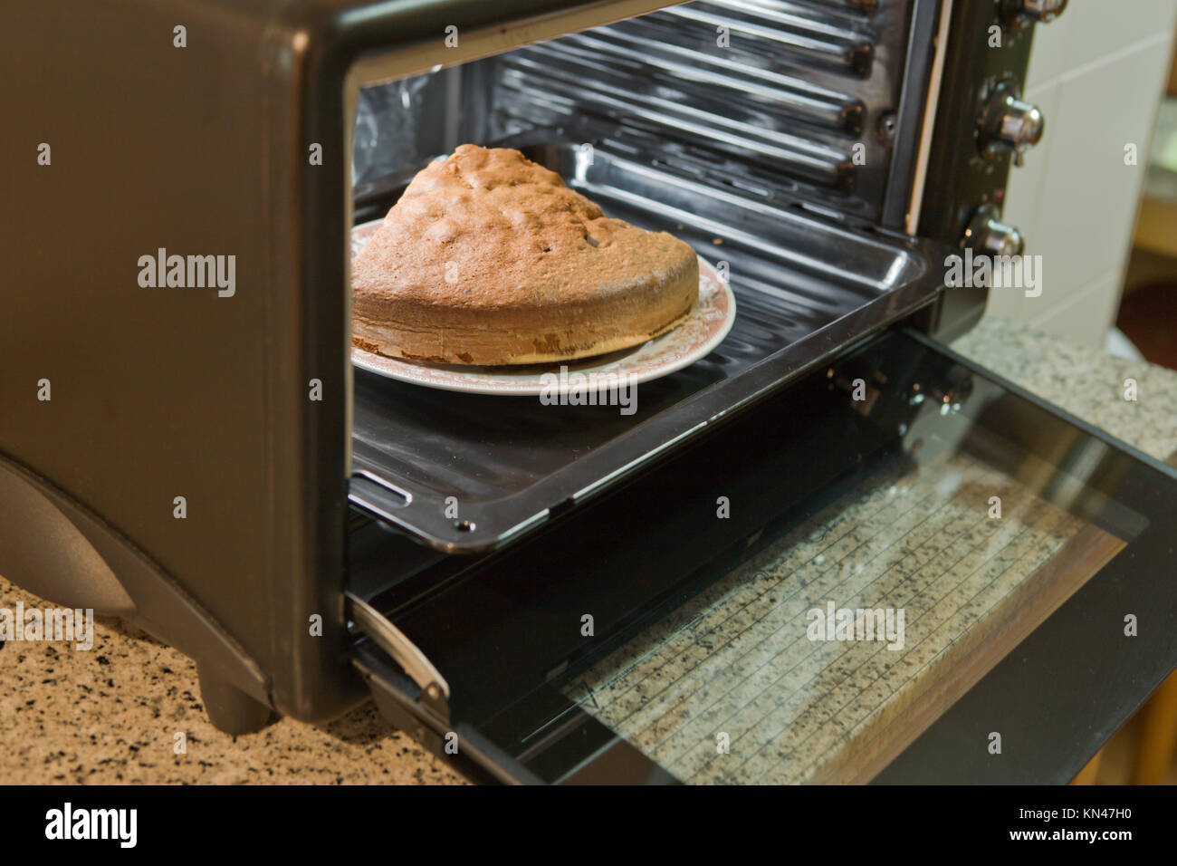 Closeup of a homemade cake in baking tin in open oven. Stock Photo