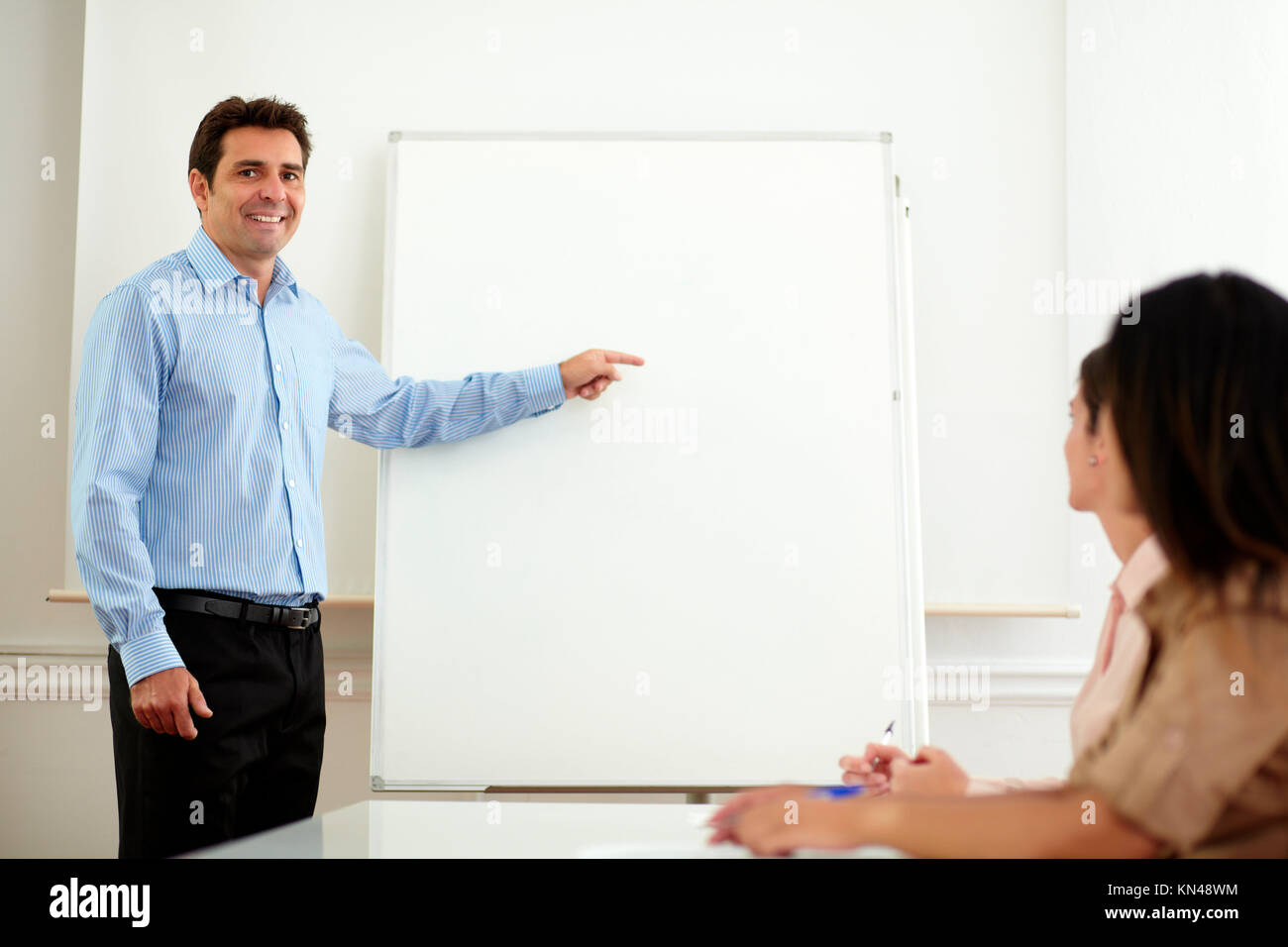 Portrait of a professional handsome man pointing at whiteboard while  standing in front of female group on office - copyspace Stock Photo - Alamy