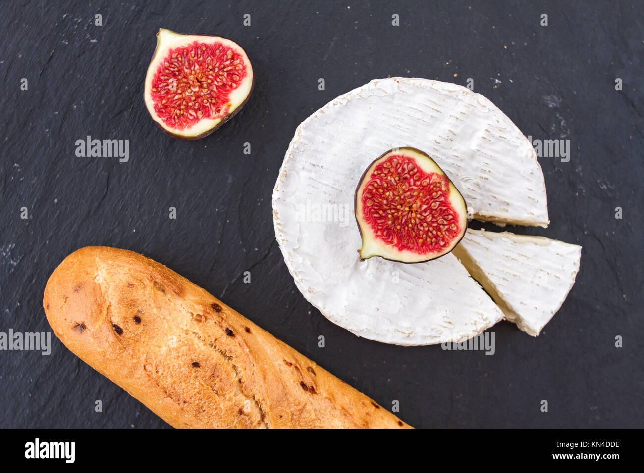 Bright juicy ripe pieces of fig fruit and creamy Swiss camembert cheese and a crispy golden fresh onion baguette for breakfast. Stock Photo