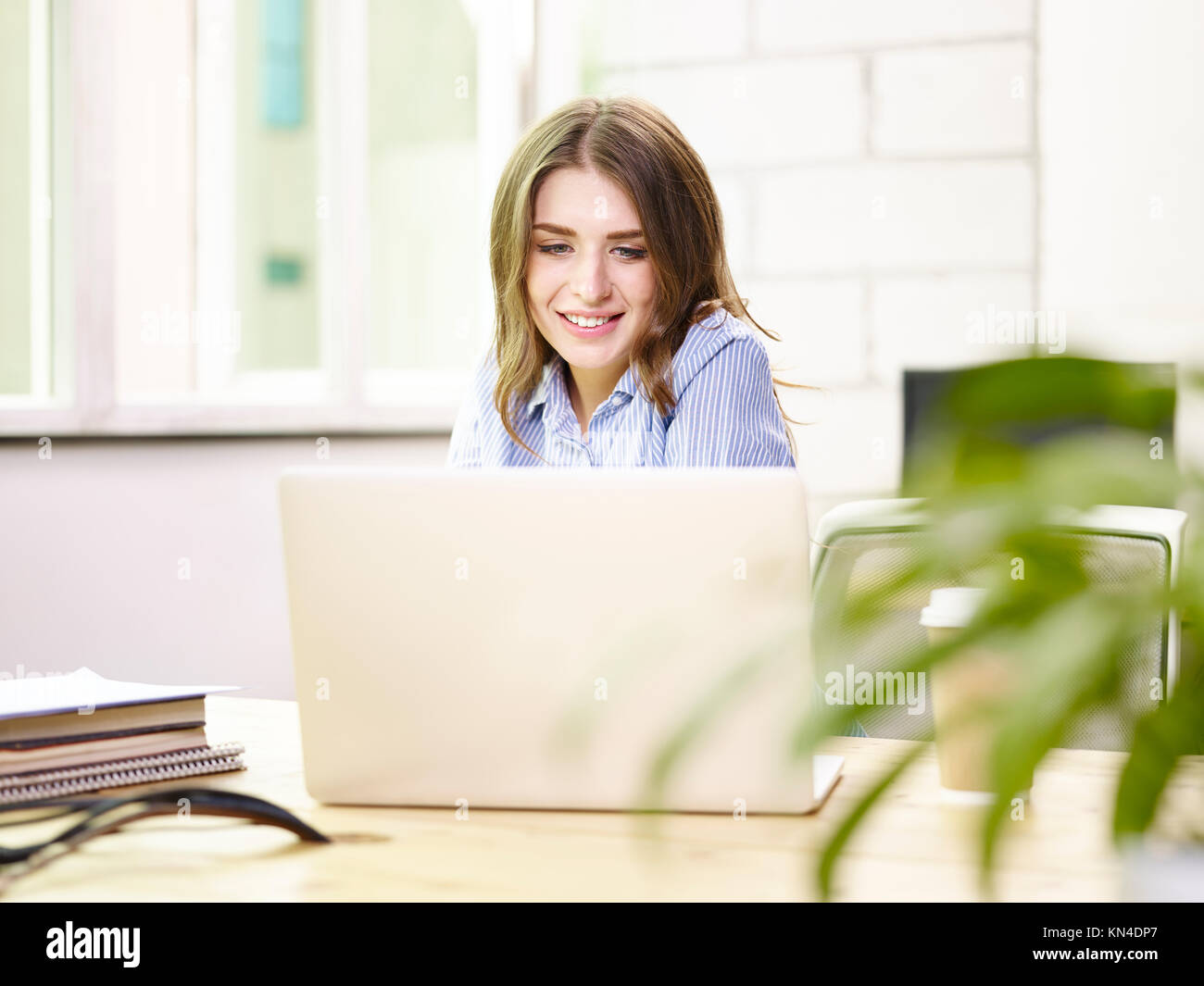 beautiful young caucasian business woman working in office using laptop computer, happy and smiling. Stock Photo