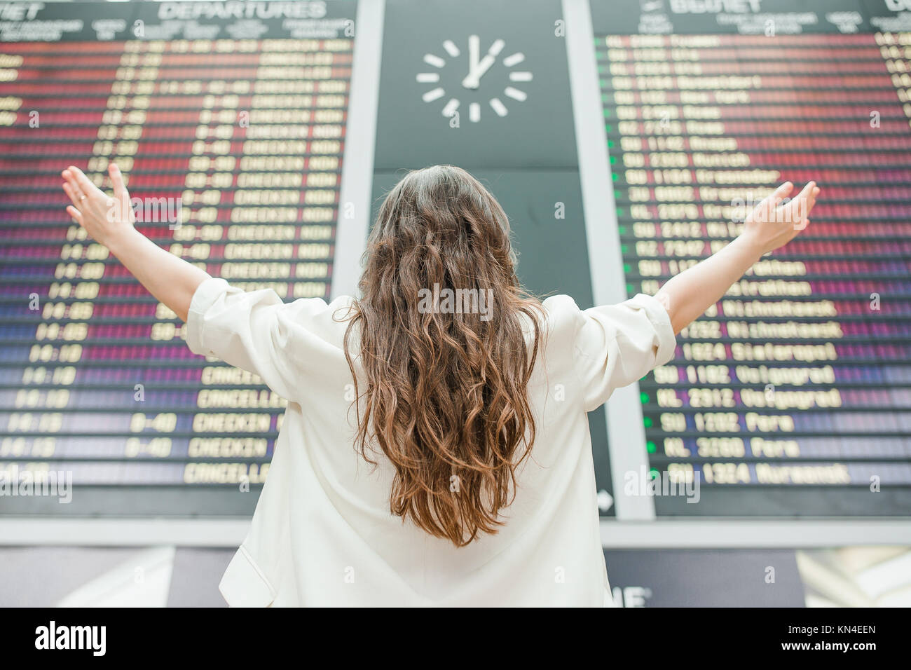 Young woman in international airport looking at the flight information ...