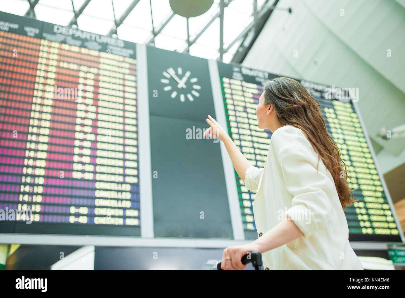 Young woman in international airport looking at the flight information ...
