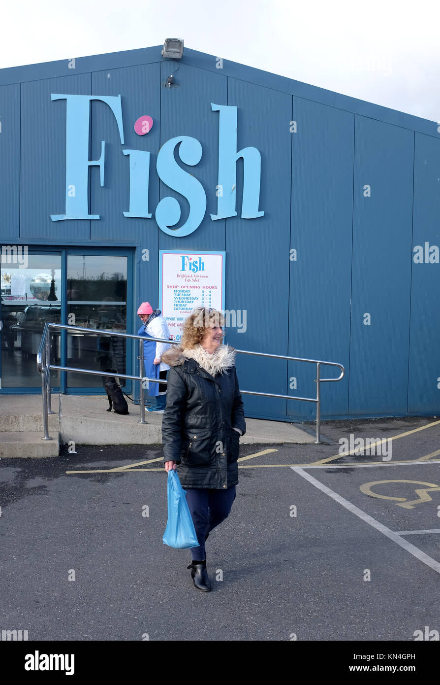 Female shopper leaving Fish the well known fresh fishmongers shop at Shoreham harbour Brighton UK Stock Photo