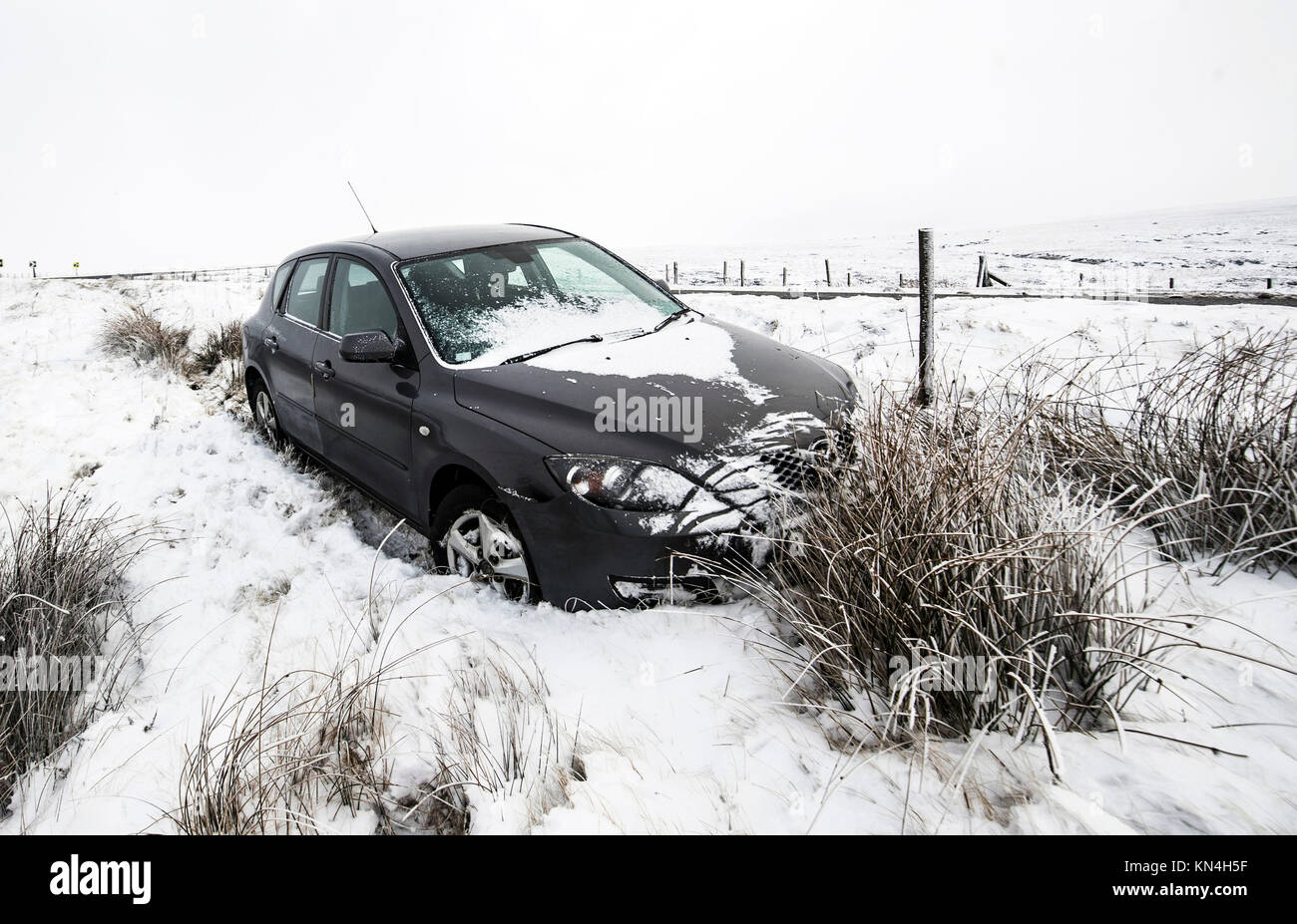 An abandoned car on the roadside on the Snake Pass in the Peak District, as heavy snowfall across parts of the UK is causing widespread disruption, closing roads and grounding flights at an airport. Stock Photo