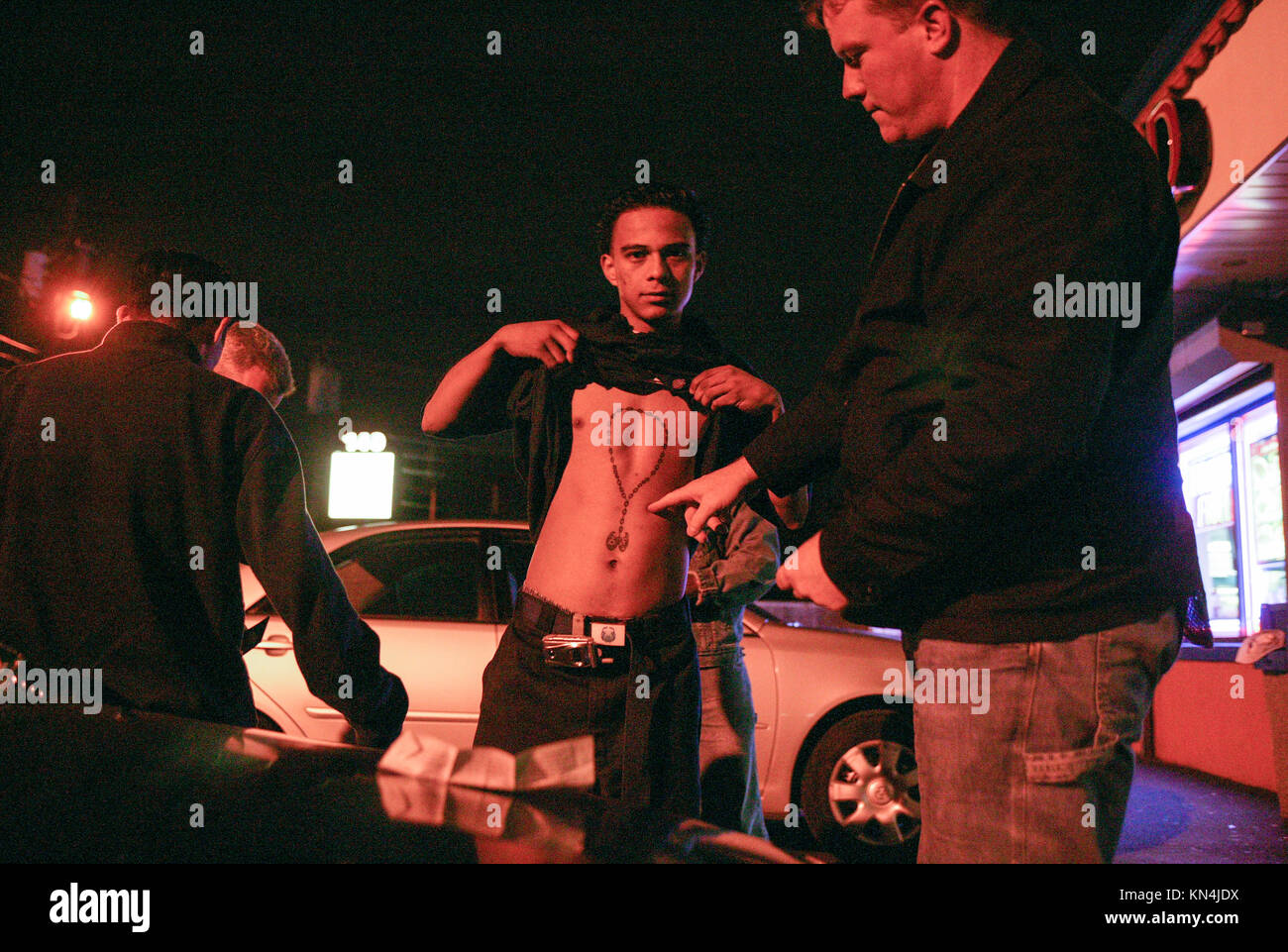 Suffolk County Police officers from the anti-gang unit check for tattoos and identity papers of possible gang members of Mara Salvatrucha 13 or MS-13 in Brentwood, New York. Many of the MS-13 members are in the U.S. illegally with false documents. The young man from Honduras, center, does have a green card and is a MS-13 member. Stock Photo