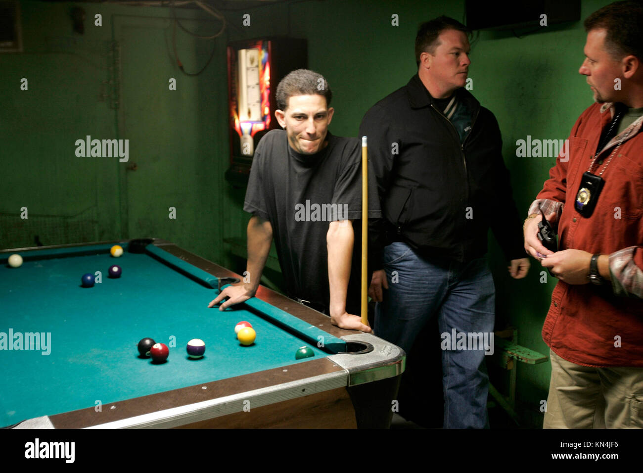Suffolk County Police officers from the anti-gang unit check identity papers of possible gang members of Mara Salvatrucha 13 or MS-13 in a pool hall in Brentwood, New York. Many of the MS-13 members are in the U.S. illegally with false documents. Stock Photo
