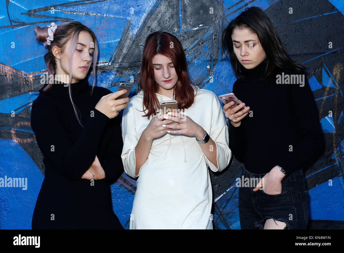 Three girls, teenagers, with mobile phones, puberty Stock Photo